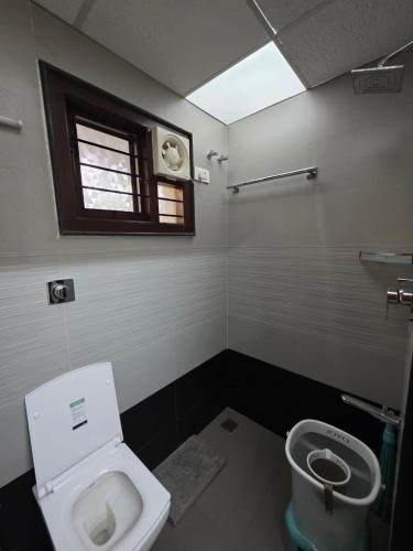 a bathroom with a toilet and a window at Ixe Stays in Mangalore
