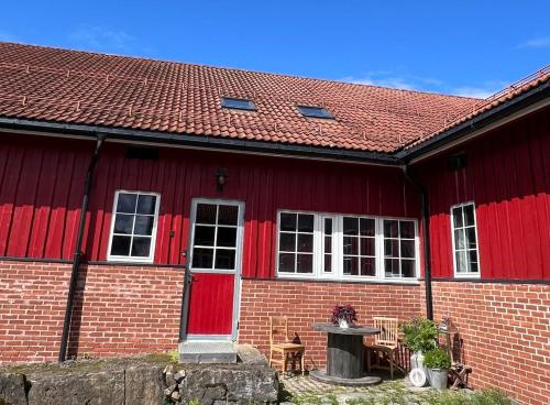 een rood bakstenen huis met rode deuren en een tafel bij Apartment in barn in Gran