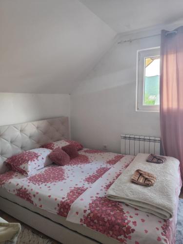 a bedroom with a bed with red and white sheets and a window at Holiday home BOŽUR in Kolašin