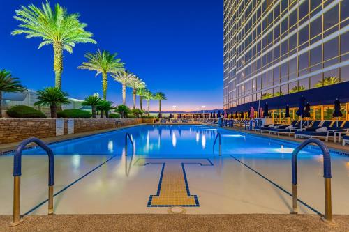 a swimming pool with palm trees and a building at Trump International Condo Hotel in Las Vegas