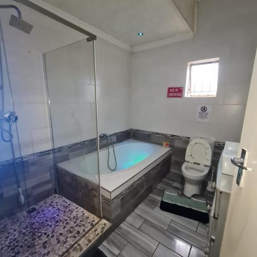 een badkamer met een ligbad en een toilet bij HostHub Guest House in Rustenburg