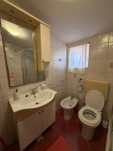 ein Badezimmer mit Waschbecken, Toilette und Spiegel in der Unterkunft Apartment House Aria in Baška Voda