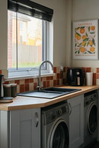 a kitchen with a sink and a washing machine at Comfortable Two Bedroom Home in Cwm-brân