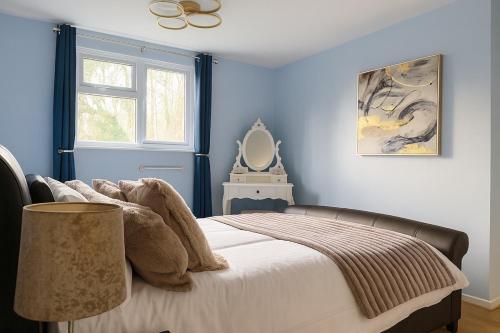 a bedroom with a bed with blue walls and a window at Comfortable Two Bedroom Home in Cwm-brân