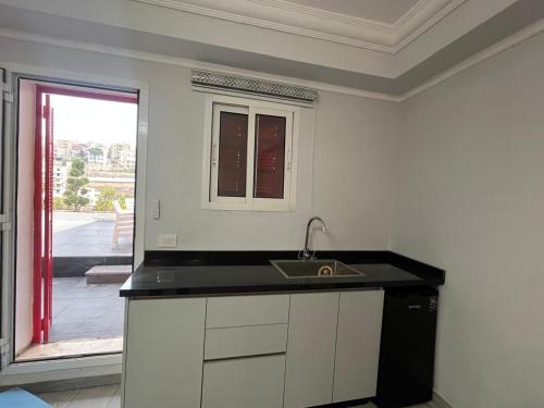 een witte keuken met een wastafel en een raam bij Terminal K Bhamdoun Hotel in Aley