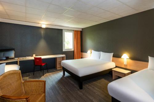 Habitación de hotel con cama, escritorio y silla en ibis Lannion, en Lannion