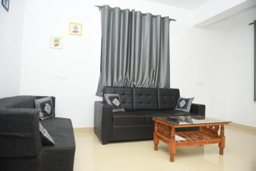 a living room with a black couch and a coffee table at Sai Homestay Panaji 2 BHK, 1 BHK and Studio Apartment in Panaji