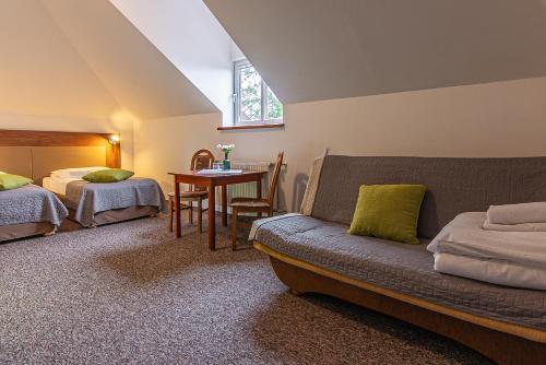 een slaapkamer met 2 bedden en een bank en een tafel bij Boży Dar in Krynica Zdrój