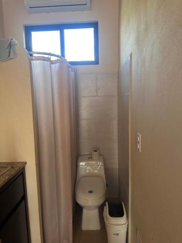 a bathroom with a toilet with a shower curtain at La Laguna in Nosara