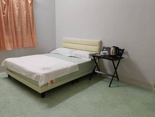 a bed in a room with a side table at Aplus two rooms in Kluang