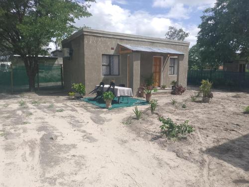 een klein huis met een tafel ervoor bij Thukhana House in Maun