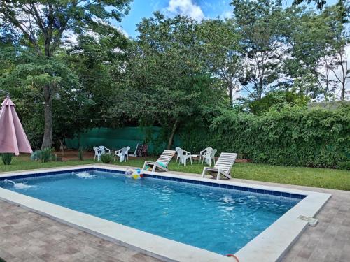 a swimming pool with chairs and a table at Posada El Encuentro in Atyrá