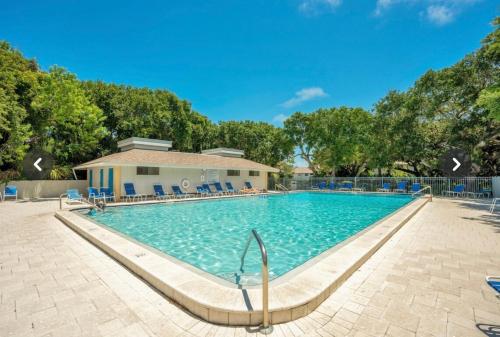 a swimming pool at a resort with blue chairs and trees at Blue Skies Seaside Veranda in New Smyrna Beach