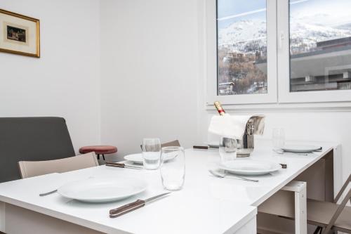 a white table with plates and glasses on it at Ski Gate - Main Street by Cervino View Experience in Breuil-Cervinia