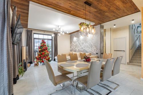 een eetkamer met een tafel en een kerstboom bij Greitser Elit Chalet in Boekovel