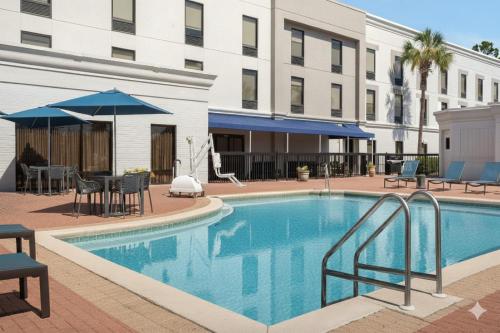 een zwembad met stoelen en parasols naast een hotel bij Hampton Inn by Hilton Panama City Beach in Panama City Beach
