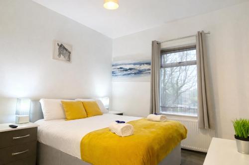 a bedroom with a bed with yellow sheets and a window at Emerald Living - Hanley, Stoke-on-Trent, sleeps 5, with free parking! in Stoke on Trent