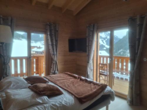a bedroom with a bed and a balcony with windows at Chalet la Fiolaz in Châtel