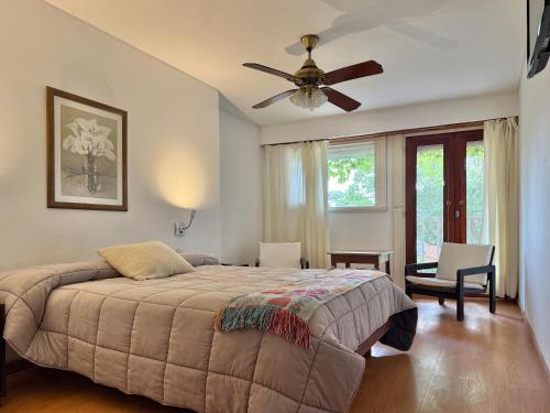 een slaapkamer met een bed en een plafondventilator bij Hotel Cervantes in Villa Gesell