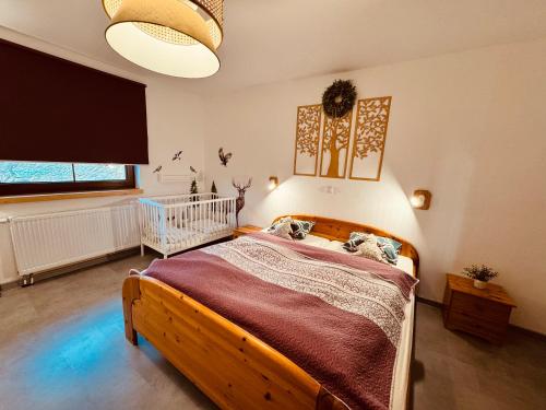 een slaapkamer met een houten bed en een wieg bij Chata Santa Claus - Rudolf i Pyszałek GÓRY SOWIE in Sokolec