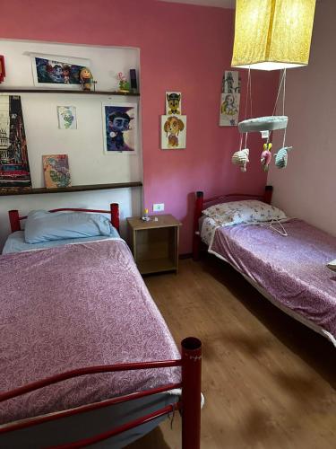 twee bedden in een kamer met roze muren bij Jacaranda 3 in Agua de Oro