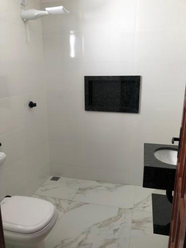 een witte badkamer met een toilet en een wastafel bij Apartamento Piúma in Piúma