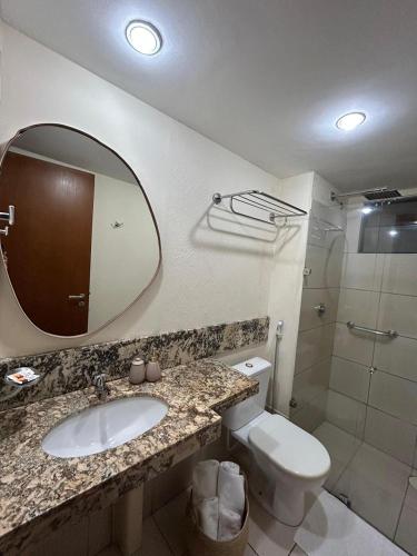 a bathroom with a sink and a toilet and a mirror at Exclusive Natal Plaza - Vista Mar - Ponta Negra in Natal