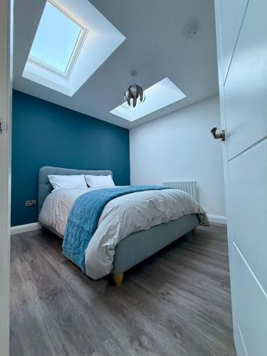 a bedroom with a bed with blue walls and a skylight at Black Dub Cottage in Allonby