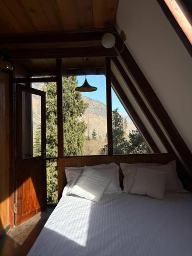 een bed in een kamer met een groot raam bij Mysa, A-frame cottage in Shirir