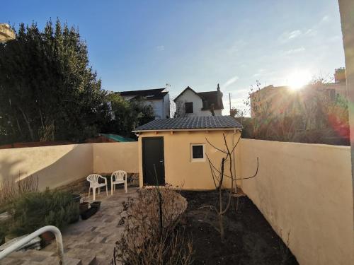 une petite maison dans une cour arrière avec une clôture dans l'établissement Independent studio 12 min from Paris, à Deuil-la-Barre