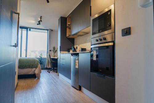 a kitchen with a stove and a tv on the wall at Suite Compacta y Elegante in Temuco