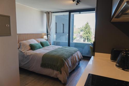 a bedroom with a bed and a large window at Suite Compacta y Elegante in Temuco