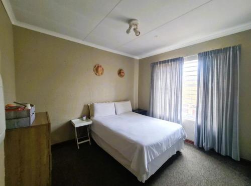 a bedroom with a white bed and a window at Blissfulnest stay two in Roodepoort