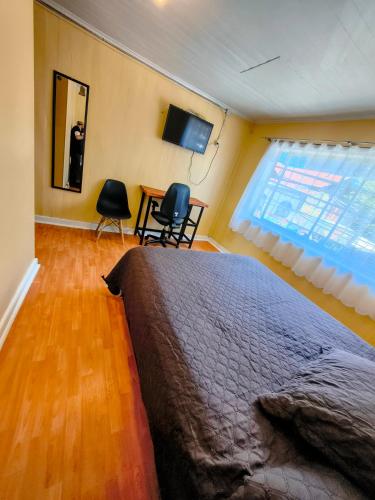 a bedroom with a bed and a table and chairs at Hostel Notro Valdivia in Valdivia