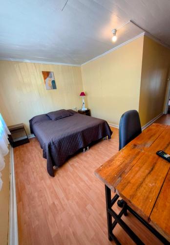 a bedroom with a bed and a wooden table at Hostel Notro Valdivia in Valdivia