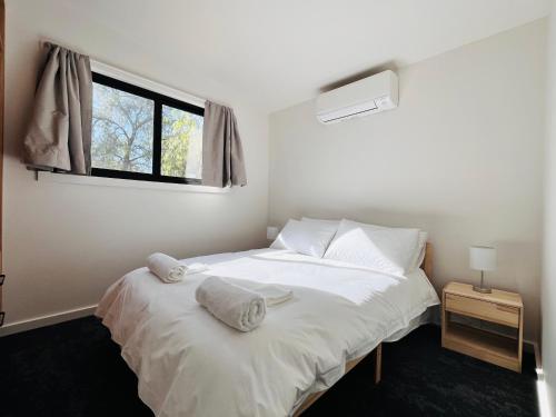 ein Schlafzimmer mit einem weißen Bett mit Handtüchern darauf in der Unterkunft Castlemaine Short Stays in Castlemaine