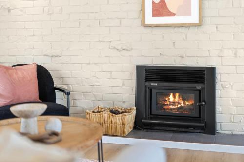a fireplace in a living room with a couch and a table at Holiday House in Central North Shore Auckland in Auckland