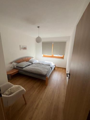 a bedroom with a bed and a chair in a room at Apartmán Blatka in Nová Pec