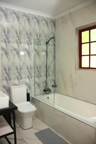 a bathroom with a tub and a toilet and a sink at Unit 35 Pendleberry grove holidays in Bela-Bela