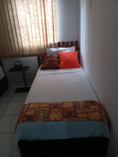 a bedroom with a bed with a red pillow at UniversiFlat in Ponta Grossa