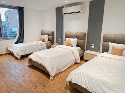 una camera d'albergo con tre letti e una finestra di Pyrs Giza Heaven a Il Cairo