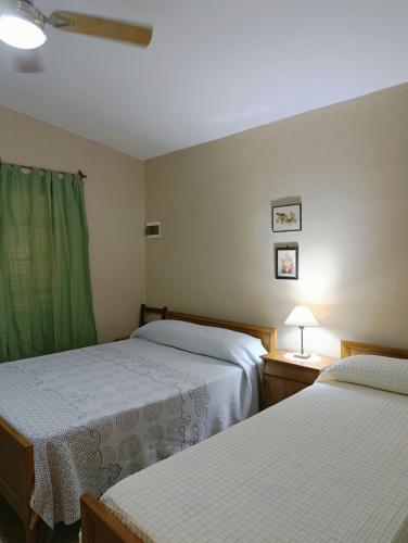 - une chambre avec 2 lits et un rideau vert dans l'établissement Casa en centro de Icho Cruz, à Villa Icho Cruz