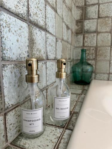 two glass bottles sitting on a counter next to a sink at L'écrin du sancy in La Bourboule