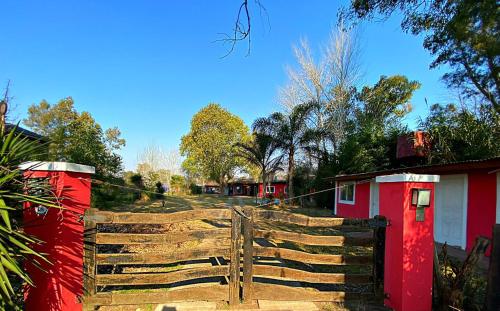 een houten hek voor een tuin met huizen bij La Arboleda - Casa de Campo in Marcos Paz