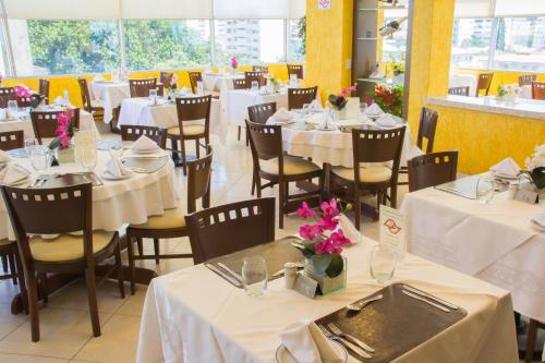 a restaurant with white tables and chairs with flowers on them at L'Opera Hotel in Sao Paulo