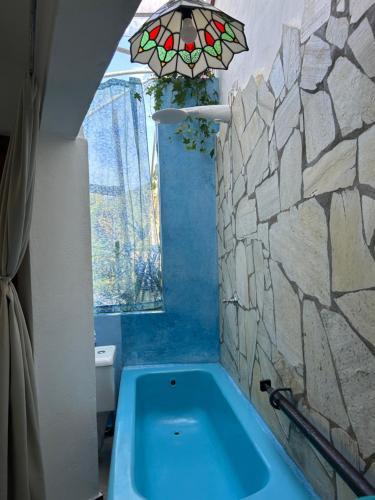 bagno con vasca blu e parete in pietra di Chalé Vista Mar a Ilhabela