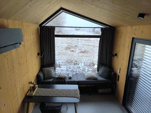 een kamer met een raam, een bank en een tafel bij Tiny House 1 im schönen Allgäu mit großem Garten, Naturnah in Bad Wurzach