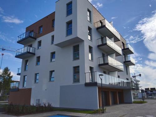 een wit gebouw met een zwembad ervoor bij Apartment J&S nr 77, blisko Aquapark Reda, Trójmiasto in Rumia