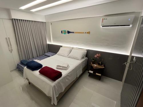 Cette petite chambre comprend un lit avec des draps blancs et rouges. dans l'établissement Melhor Apto no Centro ao lado da Praia e Comércio, à Guarapari