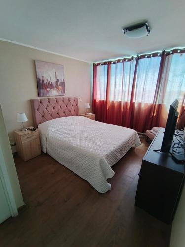 een slaapkamer met een bed en een bureau met een televisie bij Edificio Concepto in Calama